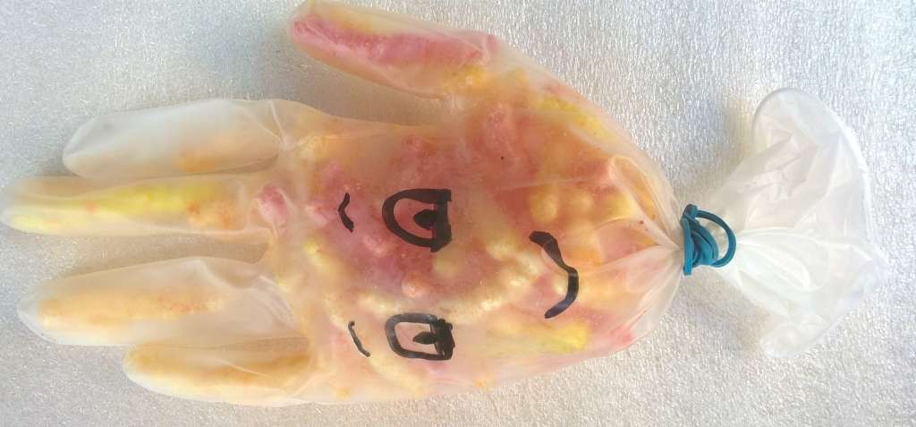 Kindertraktatie van een gevulde wegwerphandschoen met een getekend gezichtje