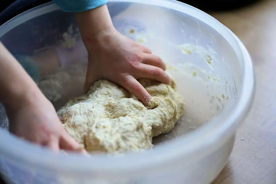 Kind kneedt pizzadeeg tijdens het samen koken